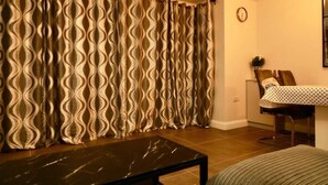 Ein Wohnzimmer mit einem gemusterten Vorhang, einem kleinen Tisch und einem Sessel.