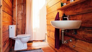 A wooden bathroom with a white toilet, a sink, and a shower curtain.
