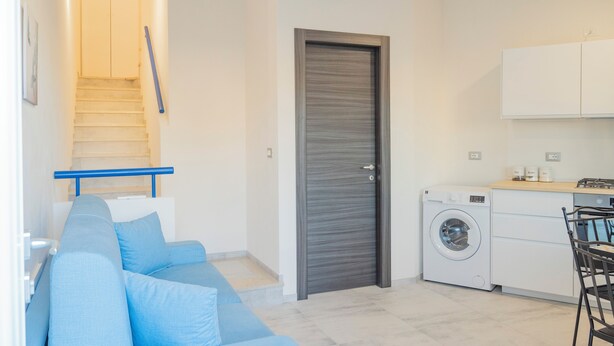 A compact living space with a staircase, a washing machine, and a kitchenette. - New apartment 3 minutes from the archaeological park and 600 meters from the sea (Marinella)