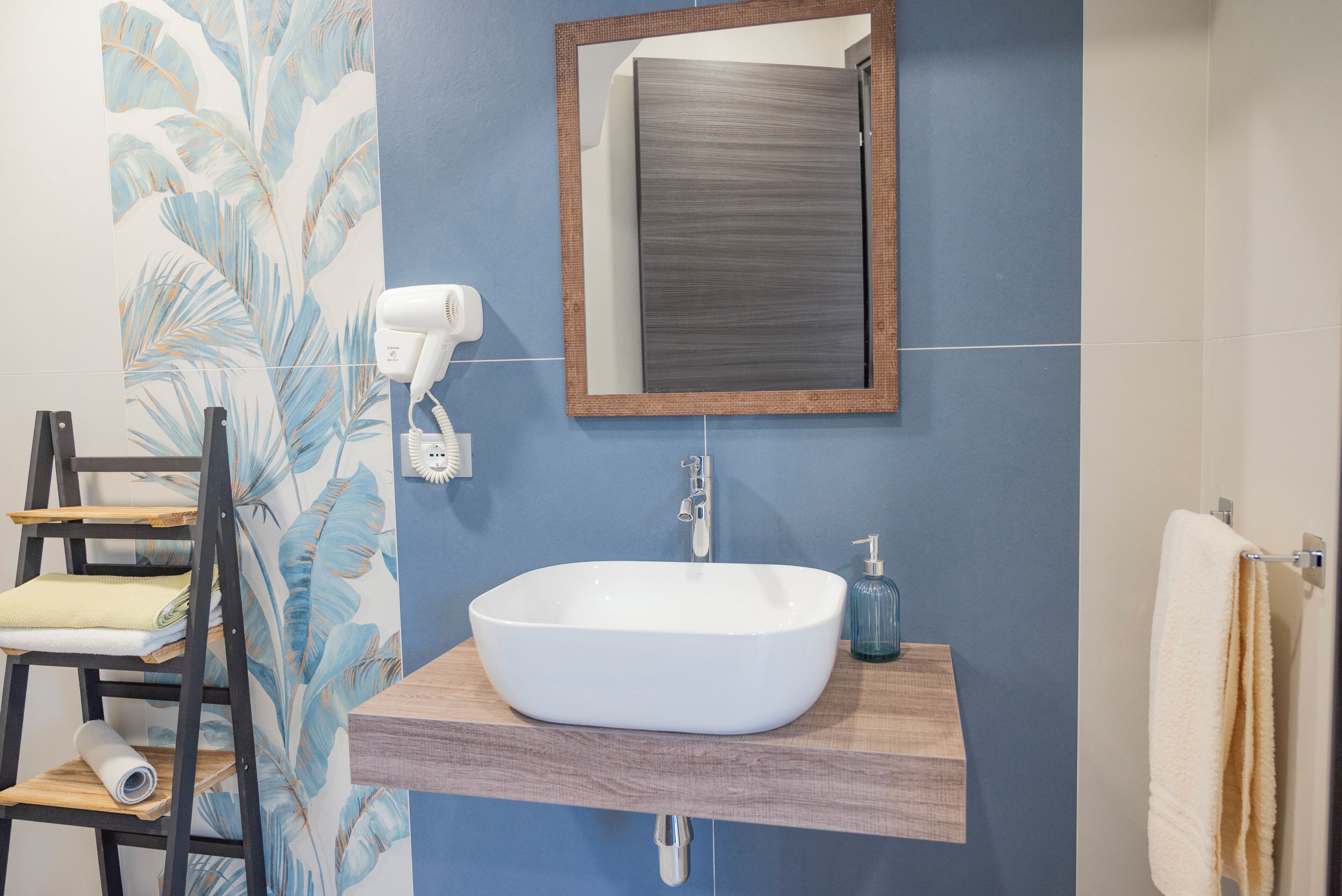 A bathroom with a white sink, wooden vanity, a towel rack, and a mirror.