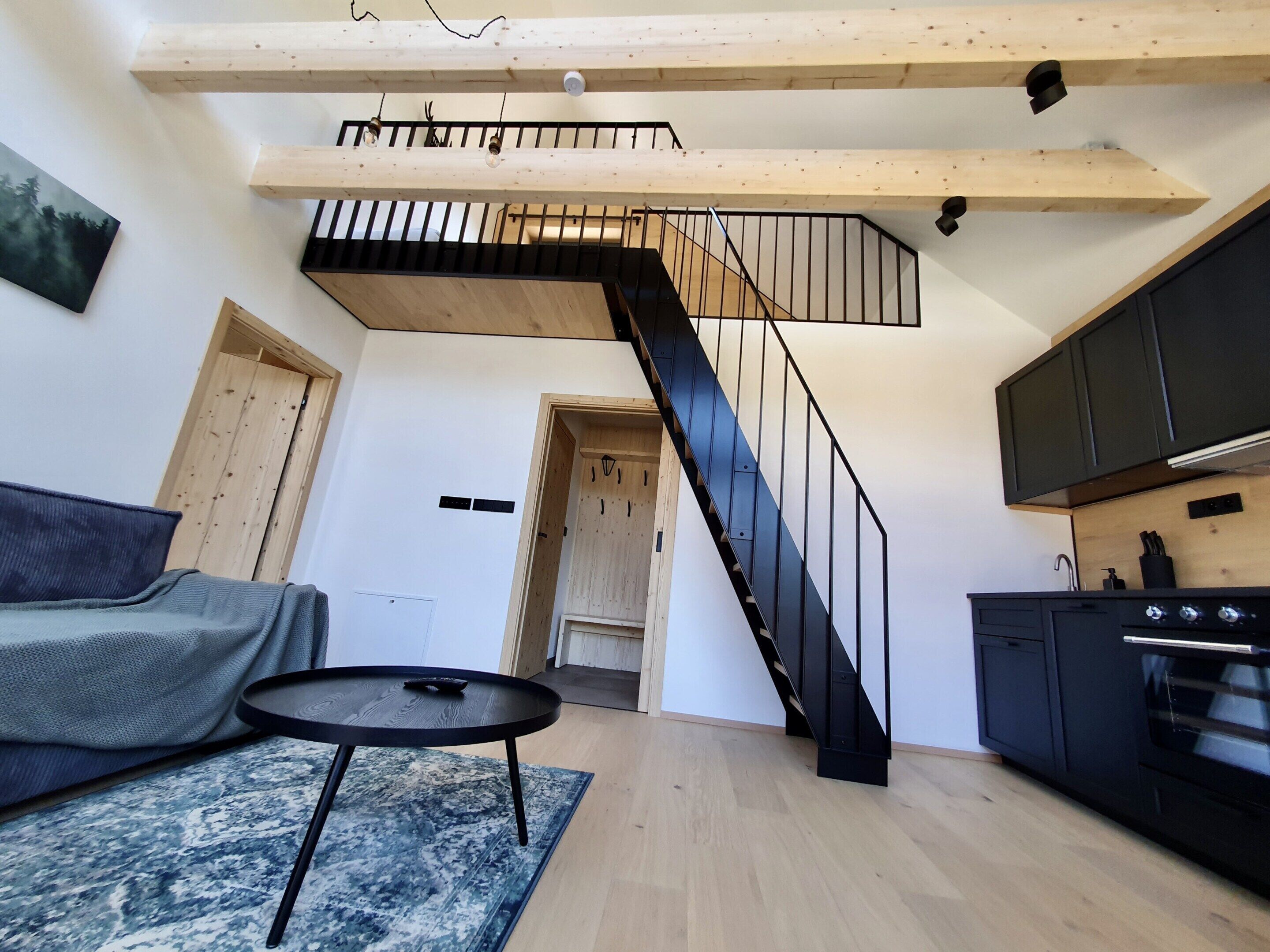 A modern interior with a staircase, a sofa, a small table, and a kitchen area.