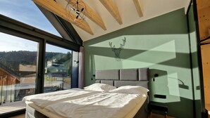Une chambre moderne dotée d’un grand lit, offrant une vue sur l’extérieur et présentant un design de plafond original.