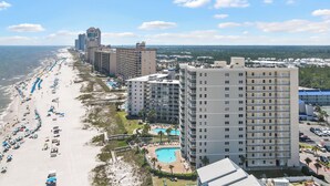 A beachfront hotel with multiple high-rise buildings, a swimming pool, and a beach with umbrellas. - ☀Sundazed☀ ~ Spectacular Beachside Condo w/Fabulous Pool at Tradewinds in OBA⛱ (Orange Beach)
