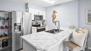 A modern kitchen with a marble countertop, stainless steel appliances, and a unique seahorse wall decoration. - ☀Sundazed☀ ~ Spectacular Beachside Condo w/Fabulous Pool at Tradewinds in OBA⛱ (Orange Beach)