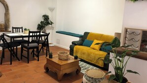 Ein Wohnzimmer mit einer Couch, Sesseln, einem Couchtisch und einem Esstisch.