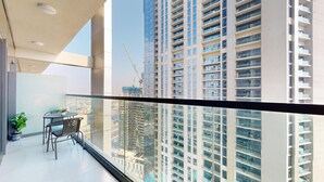 A modern apartment with a balcony, a dining area, and a view of surrounding high-rise buildings. - Calm One Bedroom l Close to Iconic Attractions (Business Bay)