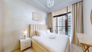A hotel room with a large bed, a bedside table with a lamp, a small table with a chair, and a window with curtains. - Calm One Bedroom l Close to Iconic Attractions (Business Bay)