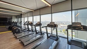 A gym with treadmills, elliptical machines, and weight benches. - Calm One Bedroom l Close to Iconic Attractions (Business Bay)