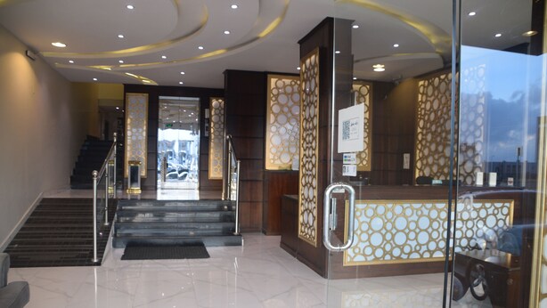 Een hotel lobby met een receptiebalie, een trap en een glazen scheiding.