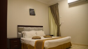 Een netjes opgemaakt bed met een hoofdbord, nachtkastje en een wandairconditioner.