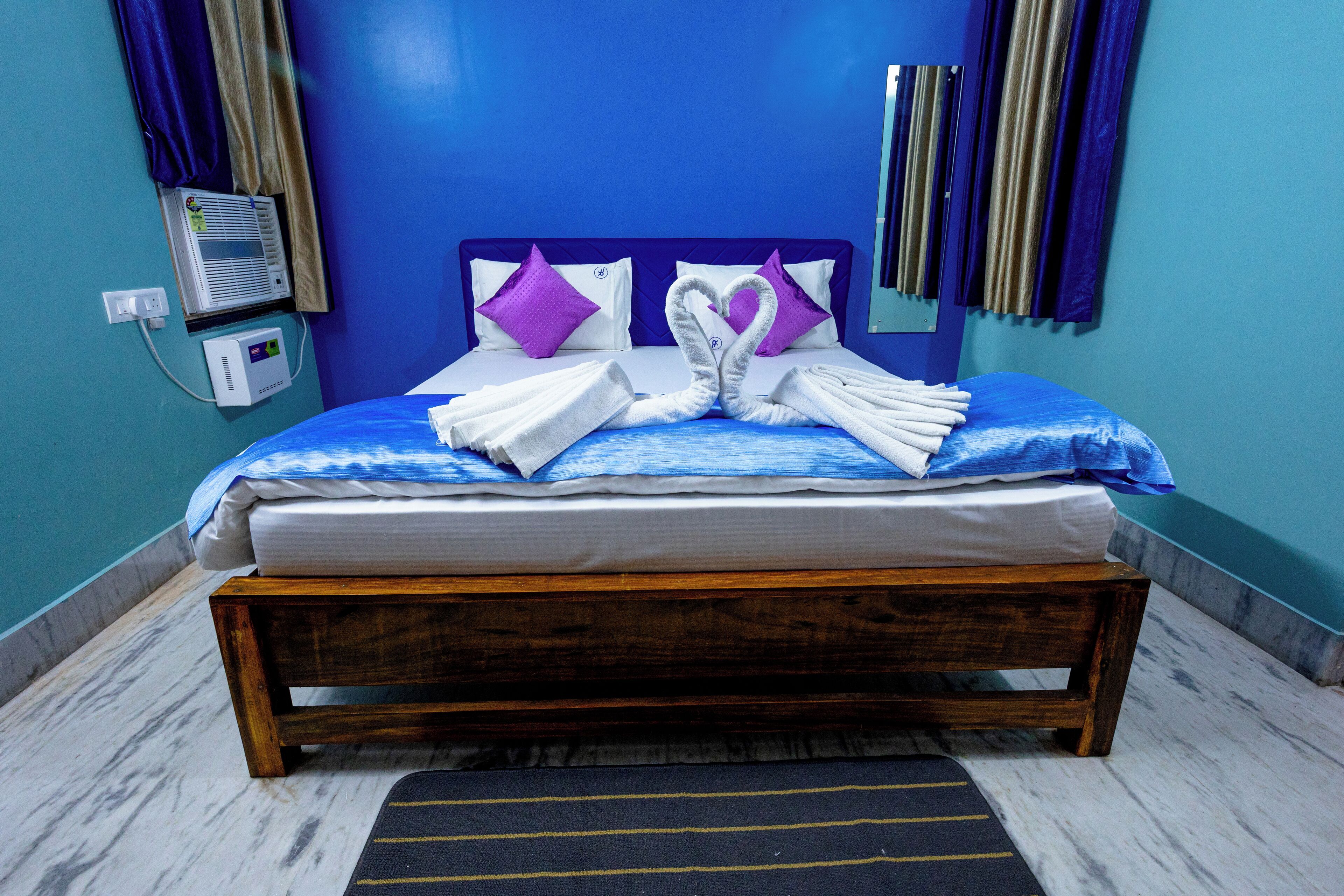 A neatly made bed with a wooden frame, a blue headboard, and purple pillows.