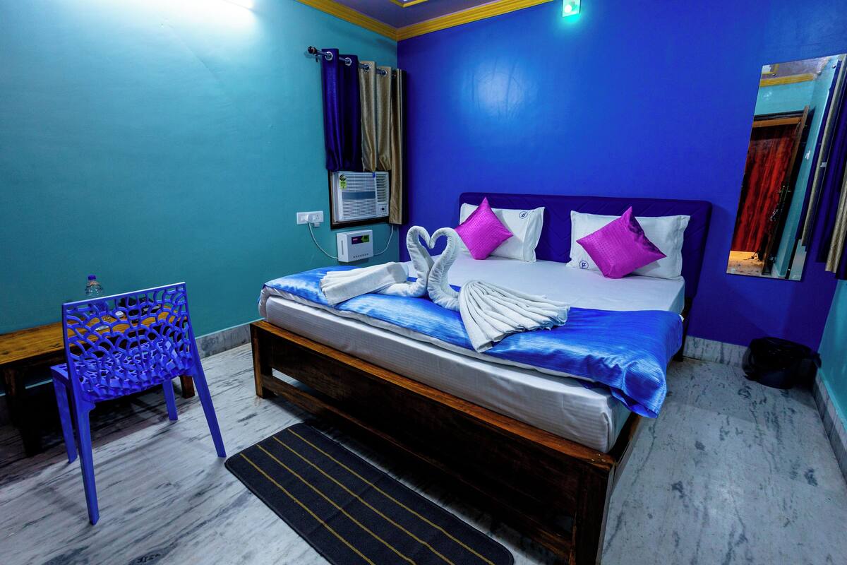 Quarto de hotel com cama, cadeira, mesa de cabeceira e ar-condicionado fixado na parede.