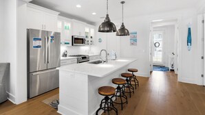 A modern kitchen with white cabinetry, stainless steel appliances, a central island with stools, and pendant lighting. - 💙Walk 2 Beach-Community Pool-4BR Sand Dollar Beach Cottage🌊 (Miramar Beach)