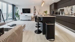A modern kitchen with a central island, a dining area with a sofa, and a large window providing natural light.