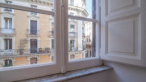 A window with a view of a building with balconies and a white door. - NICALANDRO HOUSE - ROME CENTER (Roma)