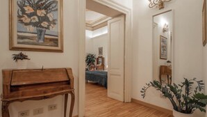 A hallway with a wooden piano, a painting, and a potted plant. - NICALANDRO HOUSE - ROME CENTER (Roma)
