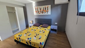 A bedroom with a bed, bedside tables, a nightstand, a wall-mounted air conditioner, and a door. - villa sophie glamour beach (Nosy Be)