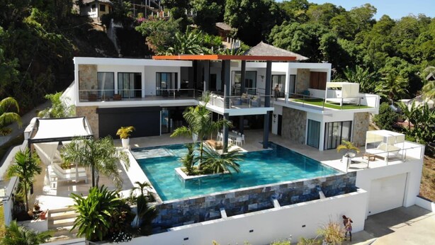 A modern two-story house with a swimming pool, surrounded by lush greenery and hills. - villa sophie glamour beach (Nosy Be)