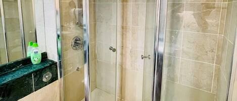 A modern bathroom with a glass-enclosed shower, a white toilet, and a black countertop with a soap dispenser.