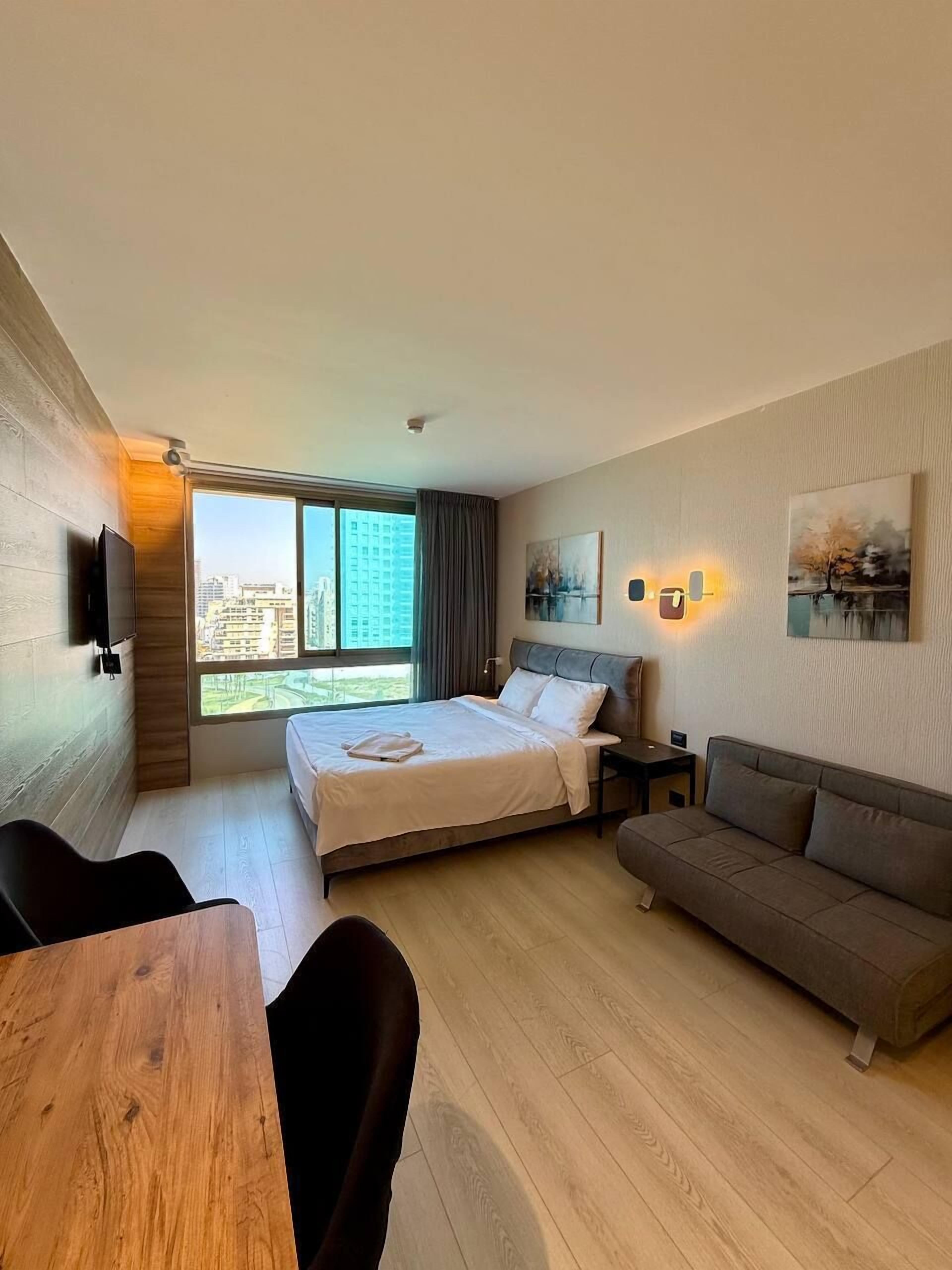 Una habitación de hotel moderna con una cama grande, un sofá, una mesa de madera y un televisor.