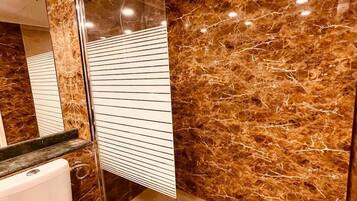 Un bagno con un water, uno specchio e una parete in marmo.