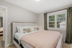 A bedroom with a bed, a window with curtains, and a door leading to another room. - The Rams' Den – King Beds, Fire Pit, Spacious Yard (Fort Collins)