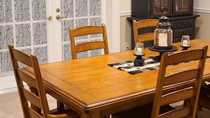 A dining room with a wooden table and chairs, a cabinet with glass doors, and a door with star decorations.
