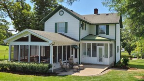 A two-story house with a covered patio and a large window overlooking a grassy yard.
