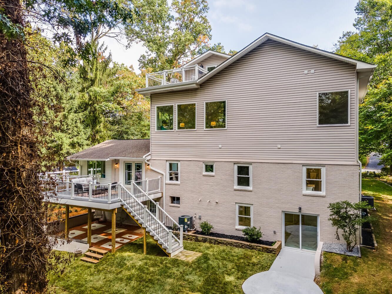 A multi-story house with a deck, a staircase, and a small garden area.