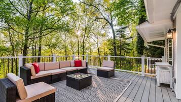 A deck with outdoor furniture, including a sofa and chairs, and a small table.