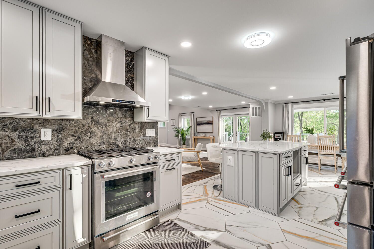 A modern kitchen with stainless steel appliances, marble countertops, and a central island.