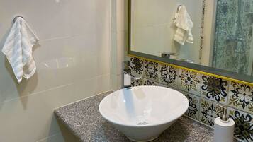 Un bagno con un lavandino bianco, uno specchio e un asciugamano appeso al muro.