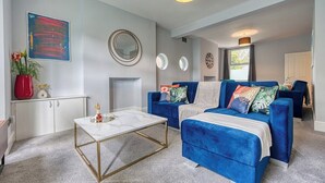 A modern living room with two blue sofas, a white coffee table, and a fireplace. - Stunning 6 bed in Nottingham - Sleeps 16 (Nottingham)