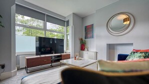 A modern living room with a large window, a flat-screen TV, a coffee table, and a sofa. - Stunning 6 bed in Nottingham - Sleeps 16 (Nottingham)