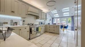A spacious kitchen with white cabinetry, a large island, and a dining area with blue chairs. - Stunning 6 bed in Nottingham - Sleeps 16 (Nottingham)