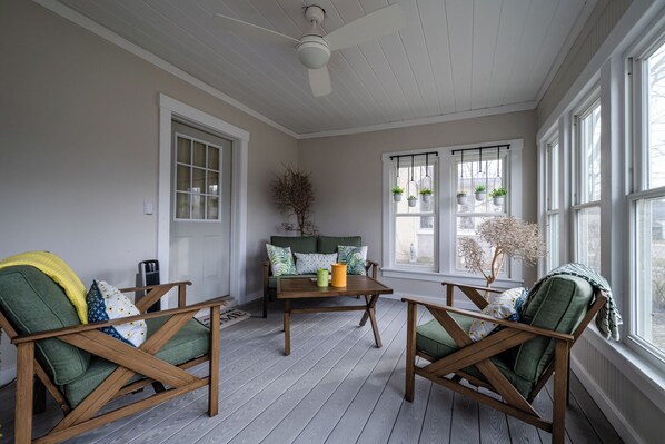A sunroom with wooden flooring, a ceiling fan, and large windows with hanging plants. - Three Oaks Home Close To Everything! Two Night Summer Min! (Three Oaks)