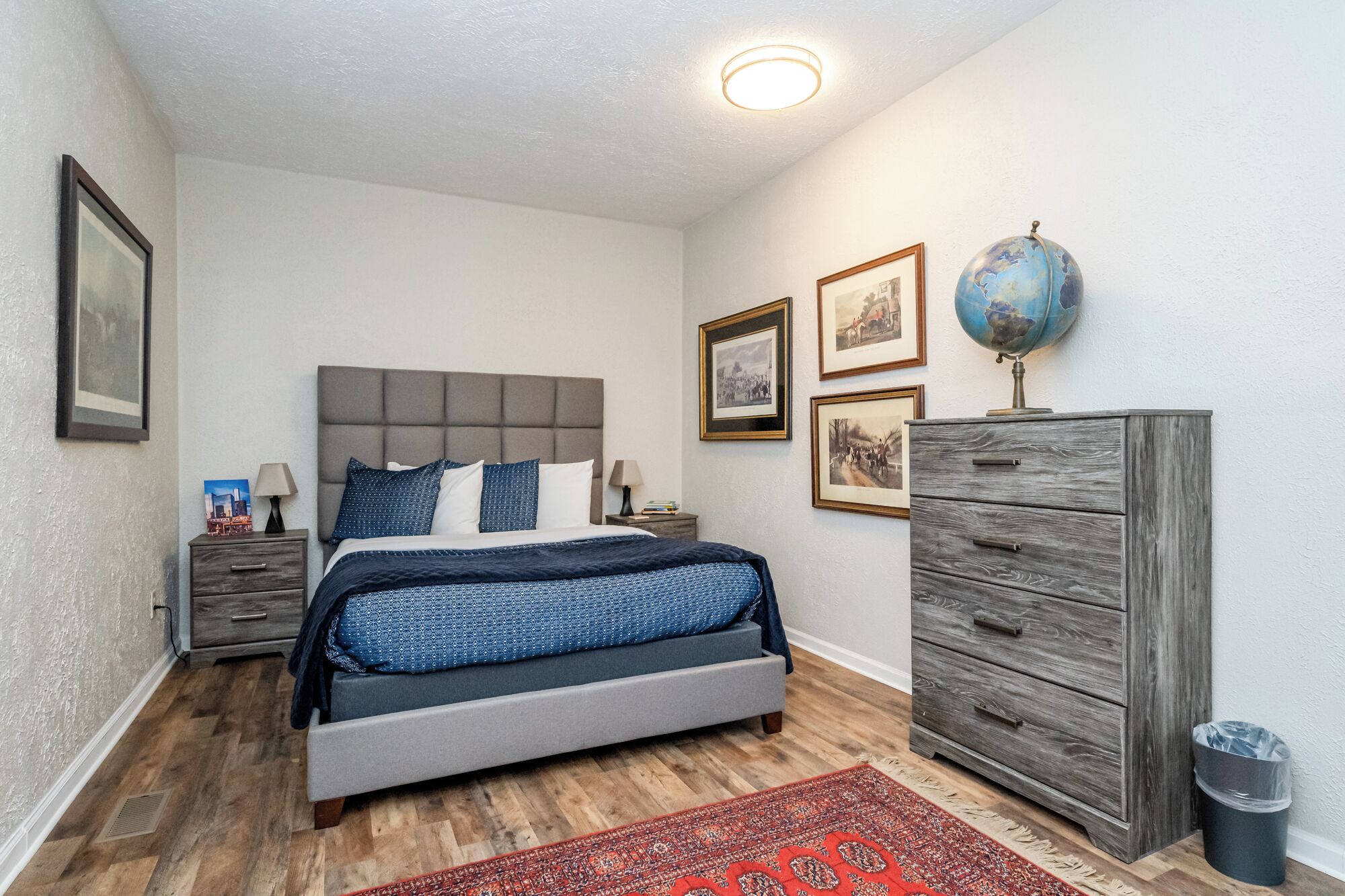 A bedroom with a bed, dresser, and a globe on top of the dresser.