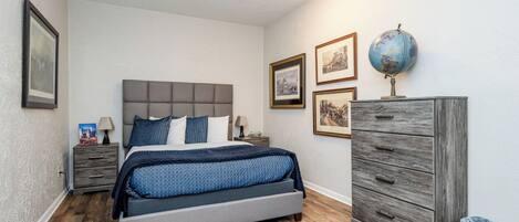 A bedroom with a bed, dresser, and a globe on top of the dresser.