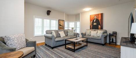 A living room with two grey sofas, a coffee table, and a patterned rug.