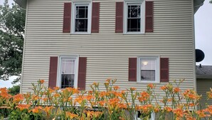 A two-story house with a gabled roof and red shutters.