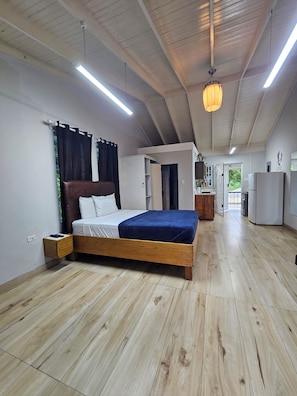 A bedroom with a wooden bed, a nightstand, a wardrobe, and a ceiling fan. - Cozy Seaview studio in Montego Bay with AC (Montego Bay)