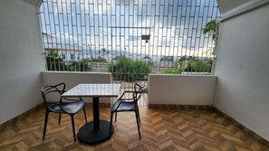 A balcony with a table and chairs, a view of the cityscape, and a patterned floor.