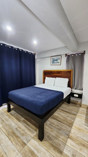 A bedroom with a bed, a nightstand, and a painting on the wall.