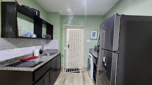 A compact kitchen with a built-in refrigerator, a washing machine, and a sink.