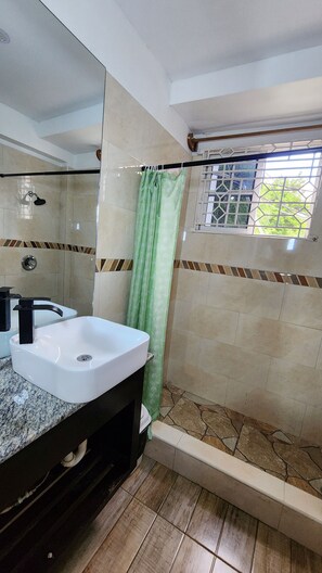 A bathroom with a white sink, a shower, and a large mirror. - Cozy Seaview studio in Montego Bay with AC (Montego Bay)