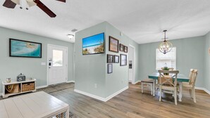 A spacious living area with a dining table, chairs, and a ceiling fan.