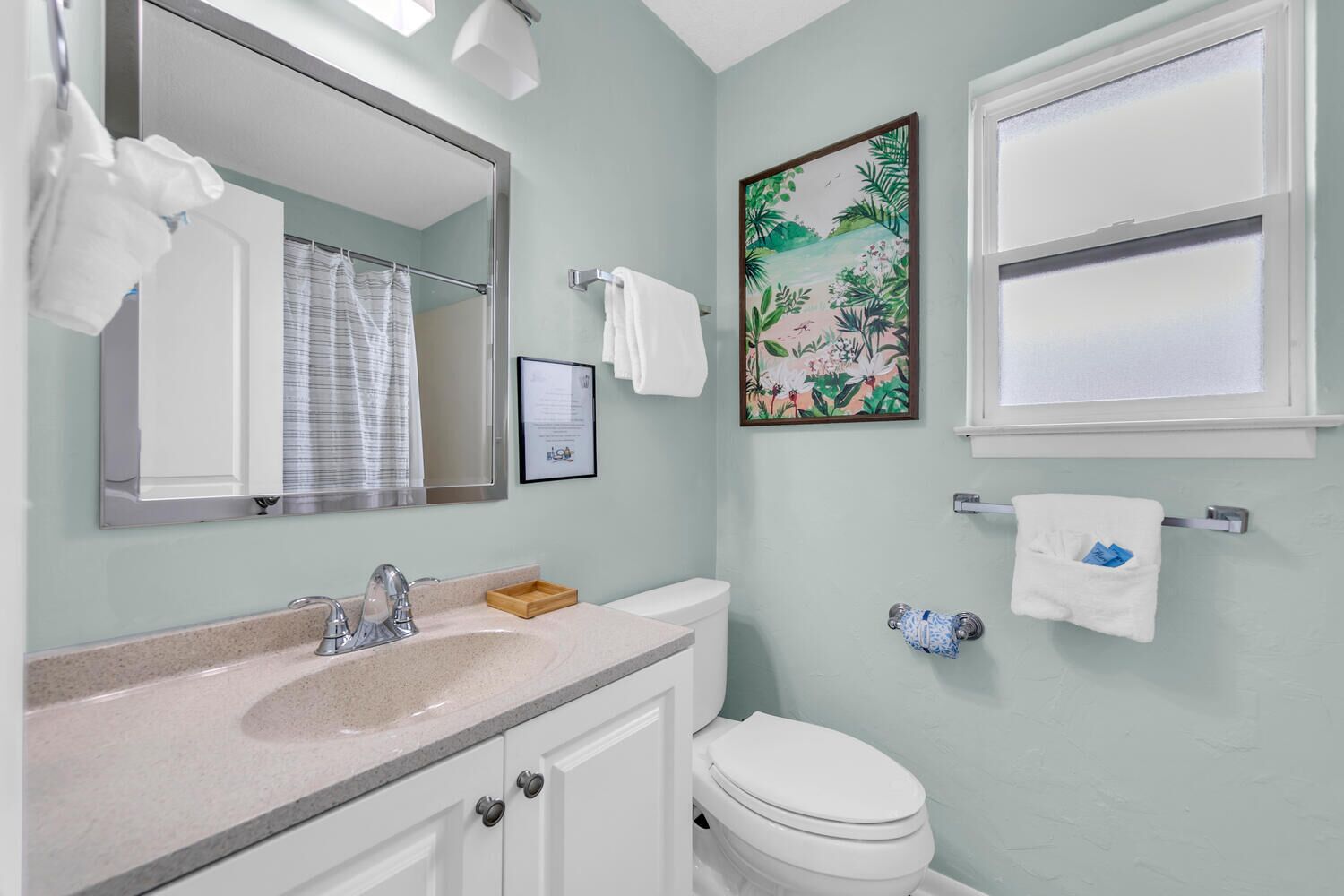 Une salle de bain équipée d’un lavabo, d’un miroir, de toilettes et de porte-serviettes.