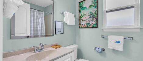 Une salle de bain équipée d’un lavabo, d’un miroir, de toilettes et de porte-serviettes.