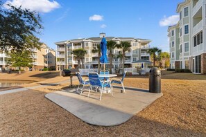 A patio area with a table and chairs, a grill, and a trash can. - Water Views- 5 Beds- Near Broadway @ Beach- Pools (Myrtle Beach)