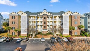 A multi-story building with a central courtyard, parking lot, and a mix of brick and siding exteriors. - Water Views- 5 Beds- Near Broadway @ Beach- Pools (Myrtle Beach)